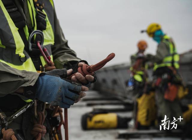 墙面灯光维护人员正在用绳索打“双渔人结”，确保设备绑紧可靠。