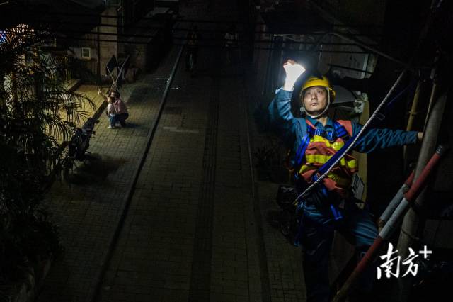 广州市越秀区惠吉西路，路灯维护人员正在更换LED灯，偶有街坊从底下经过。